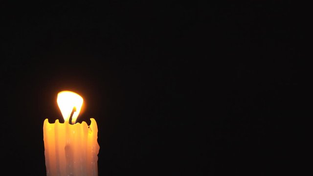 The flame of a candle sways under the breath of a breeze. A rainbow halo appears around the flame. Halo occurs due to the use of a diffraction grating in front of the lens