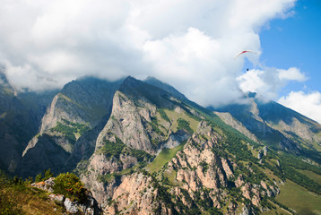 Fototapeta premium view of the valley and mountains, paraglider flying in the sky, clear summer day, chegemsky gorge