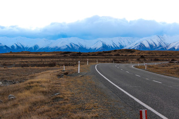 Windy, isolated road leading to snow-capped mountains. 