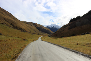 Windy dirt road leading to snow capped mountains. 