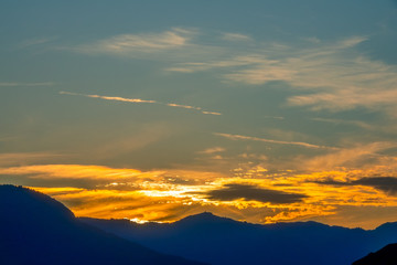 Golden Sunset Clouds Over the Silhouettes of Mountains