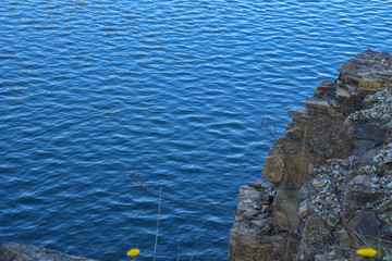 Stone rocks near water, on the background of lake, river, sea, ocean. Blue clear water. Artificial reservoirs