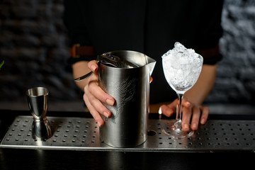 close-up female hand holds metal mixing cup with strainer