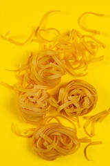 Raw noodles in a plate on anyellow background