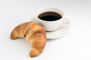 a croissant and a Cup of black coffee on a white background