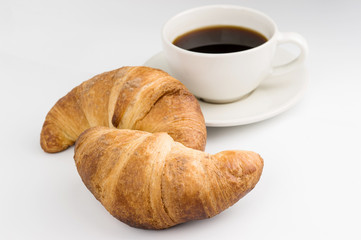 two fresh croissants and a Cup of black coffee on a white background
