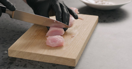 man hands slicing turkey fillet on oak board