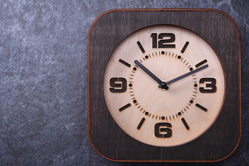 Wooden clock made in hand on wooden background. Close-up. Place for text.