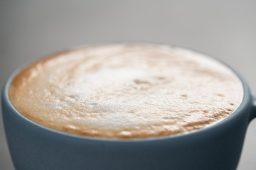 Fresh cappuccino in blue cup closeup