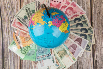 The globe on World money currency on wooden table.