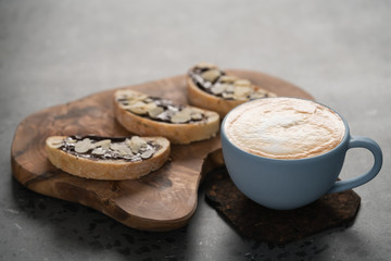 Fresh cappuccino in blue cup with toasts with chocolate spread on concrete background
