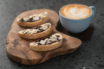 Fresh cappuccino in blue cup with toasts with chocolate spread on concrete background