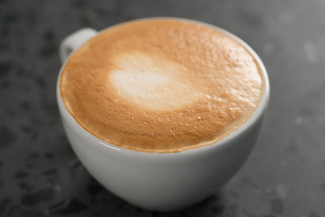Fresh cappuccino in white cup on concrete background