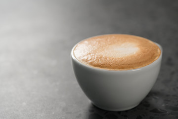 Fresh cappuccino in white cup on concrete background