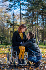 Fototapeta na wymiar Young disabled woman in a wheelchair with boyfriend. Man with disabled girl in a wheelchair