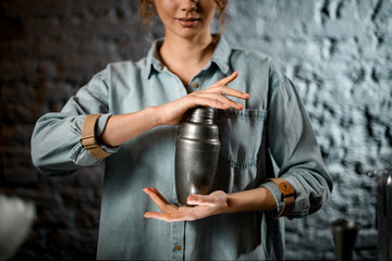 smiling bartender girl holds metal shaker at bar