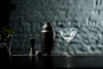 Close-up. View of bar counter on which stands metal shaker and glass