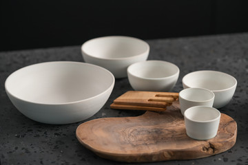 Empty matt white ceramic handmade tableware set on concrete countertop