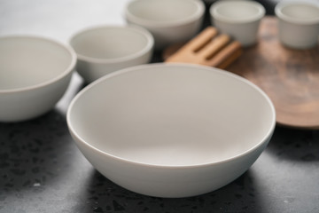 Fototapeta na wymiar Empty matt white ceramic handmade tableware set on concrete countertop