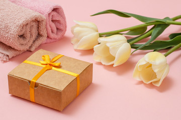 Gift box with tulip flowers on the pink background.
