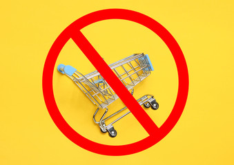 Mini shopping trolley for shopping on yellow background with prohibition sign.