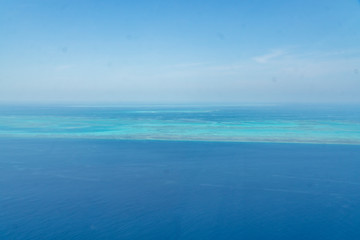 Fototapeta na wymiar Great Barrier Reef Blue Ocean Sea view. Beautiful aqua & turquoise waters, with coral reef patterns in the ocean. View from helicopter, on vacation. Marine life, global warming, protection, island