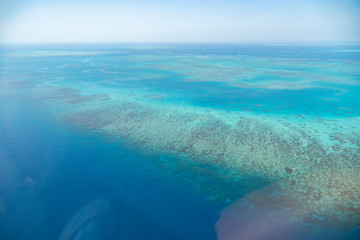 Great Barrier Reef Blue Ocean Sea view. Beautiful aqua & turquoise waters, with coral reef patterns in the ocean. View from helicopter, on vacation. Marine life, global warming, protection, island