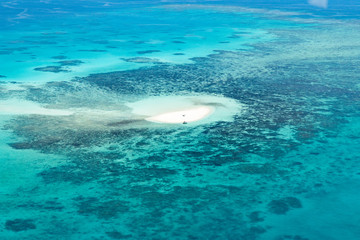 Naklejka premium Island in Great Barrier Reef Blue Sea view. Beautiful aqua & turquoise waters, with sand, coral reef patterns in the ocean. View from helicopter, on vacation. Tropical, paradise, holiday concepts