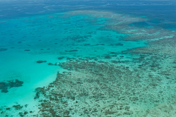 Obraz na płótnie Canvas Great Barrier Reef Blue Ocean Sea view. Beautiful aqua & turquoise waters, with coral reef patterns in the ocean. View from helicopter, on vacation. Marine life, global warming, protection, island