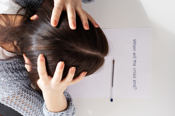 Fototapeta premium Financial collapse and unemployment. Female hands write on a piece of paper when the crisis will end