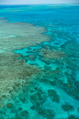 Naklejka na ściany i meble Great Barrier Reef Blue Ocean Sea view. Beautiful aqua & turquoise waters, with coral reef patterns in the ocean. View from helicopter, on vacation. Marine life, global warming, protection, island