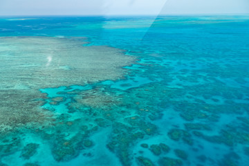 Fototapeta na wymiar Great Barrier Reef Blue Ocean Sea view. Beautiful aqua & turquoise waters, with coral reef patterns in the ocean. View from helicopter, on vacation. Marine life, global warming, protection, island