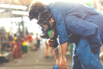 Man wearing a Toxic protective mask in factory. Biohazard. Engineering man with gas mask carried a friend out of the factory in the event of a gas leak.