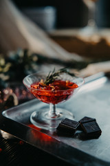 a glass with a cocktail of red color with rosemary on a dark background