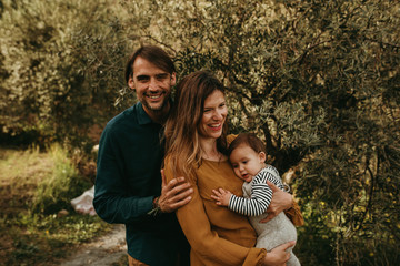 Smiling couple posing with their son outdoors. Young family concept. Mother holds the baby in the arms.