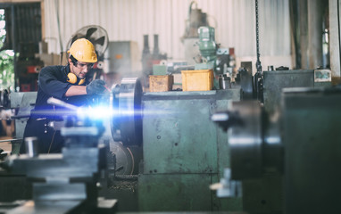 Man Worker at industrial factory wearing uniform and hardhats. Mechanical engineer working at lathe industry factory.