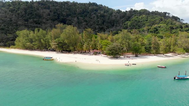 Aerial of tourist on a small tropical island with blue water white sand beach. Only accessible by long tail tourism boat