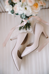 Bridal morning details composition. Top view of wedding rings, beautiful bouquet of pink flowers with ribbons, boutonniere and leather shoes. Flat lay.