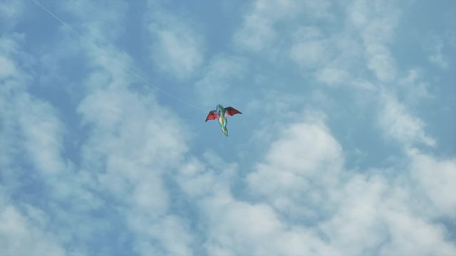 Dragon kite flying against blue sky and patchy clouds. Low angle view.