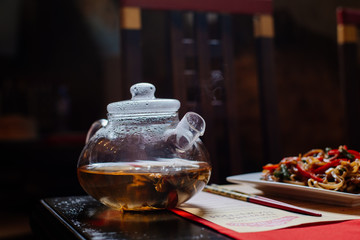 a glass teapot in which Chinese green tea is brewed. Steam comes from the spout of the kettle