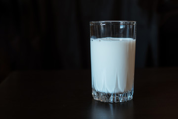 One glass with milk on a black background