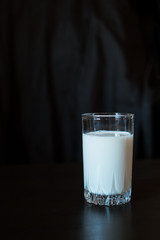 One glass with milk on a black background
