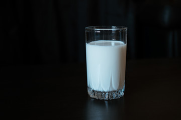 One glass with milk on a black background