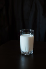 One glass with milk on a black background
