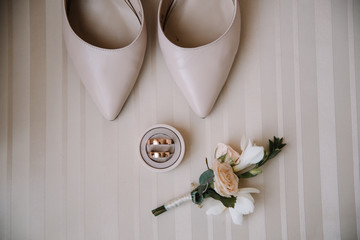 Bridal morning details composition. Top view of wedding rings, beautiful bouquet of pink flowers with ribbons, boutonniere and leather shoes. Flat lay.