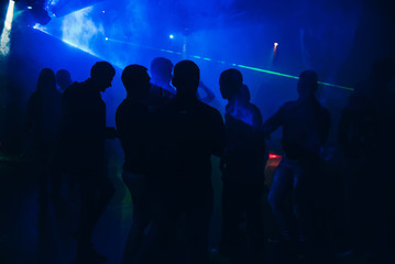 silhouettes of people dancing in nightclub on dance floor at party