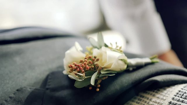 A groom's corsage on his suit that lays on the bed
