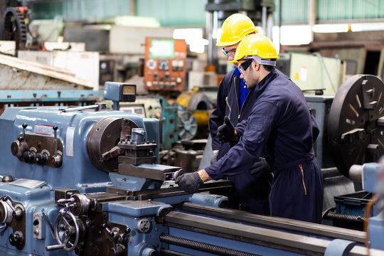 Professional Mechanical Engineer team Working on Personal Computer at Metal lathe industrial manufacturing factory. Engineer Operating  lathe Machinery. Product quality Inspection