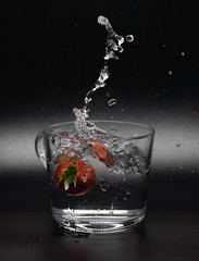 Fresh fruit falling into a glass filled with water.