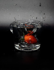 Fresh fruit falling into a glass filled with water.